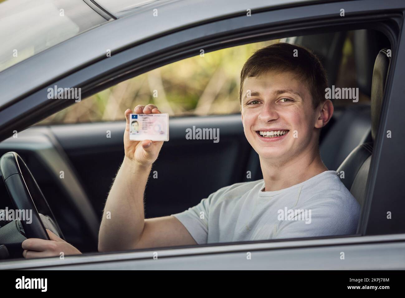Happy and proud guy showing his driver license out of the car window Stock Photo
