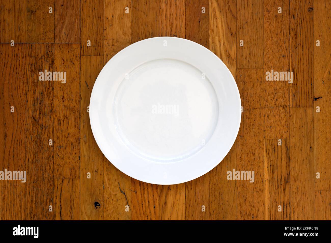 Empty white plate on wooden surface as mockup copy space, top view Stock Photo