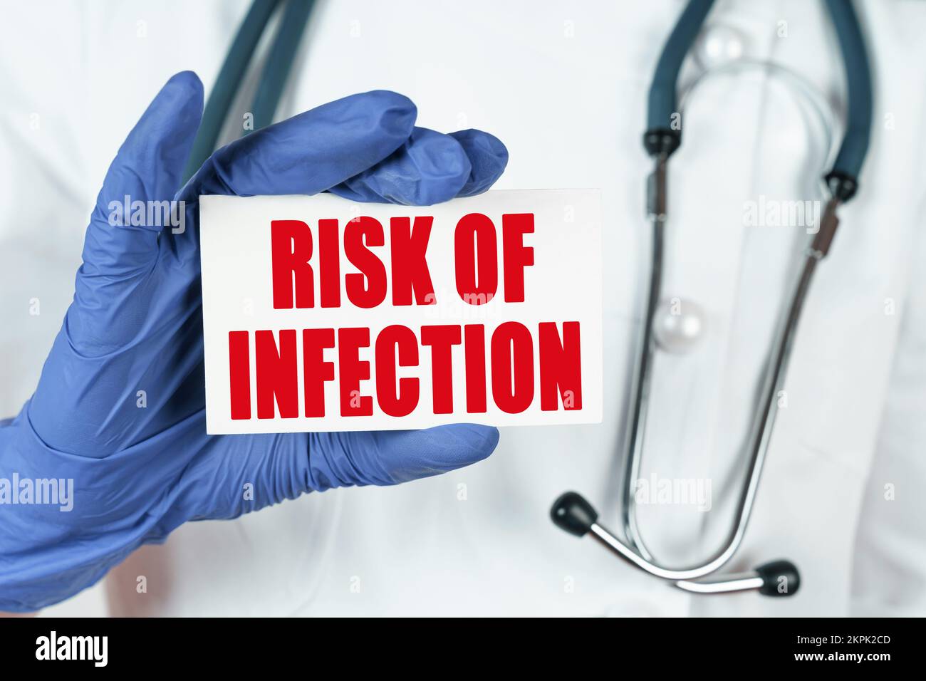 Medicine concept. The doctor holds a business card that says - RISK OF INFECTION Stock Photo