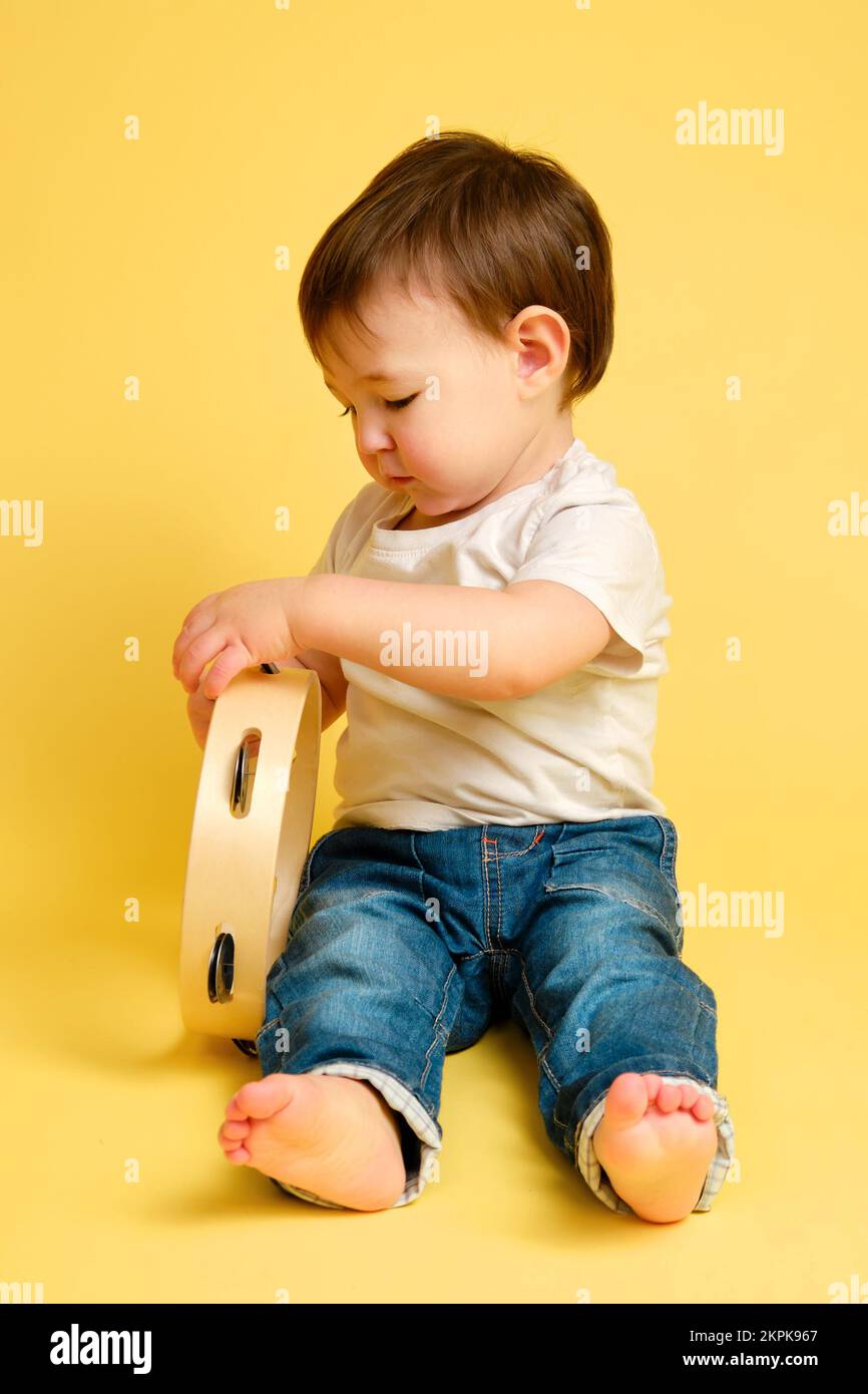 Toddler baby plays the tambourine, a child with a percussion musical