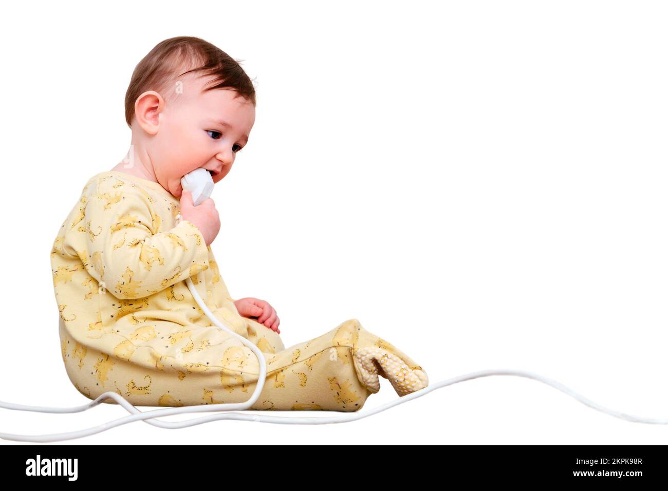 Toddler baby boy gnaws electrical wires while sitting on the floor