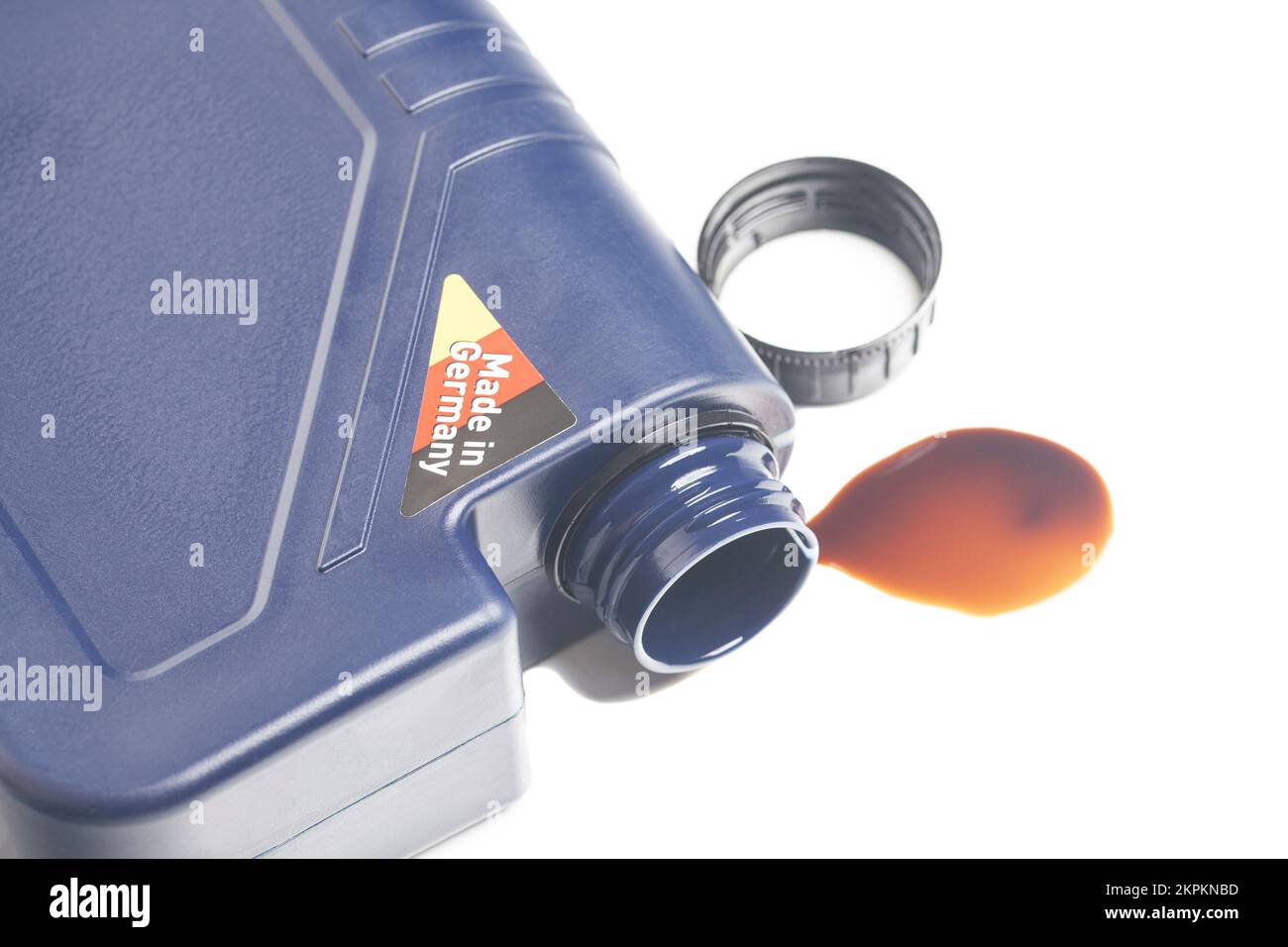 open engine oil bottle with a puddle of engine oil isolated on white