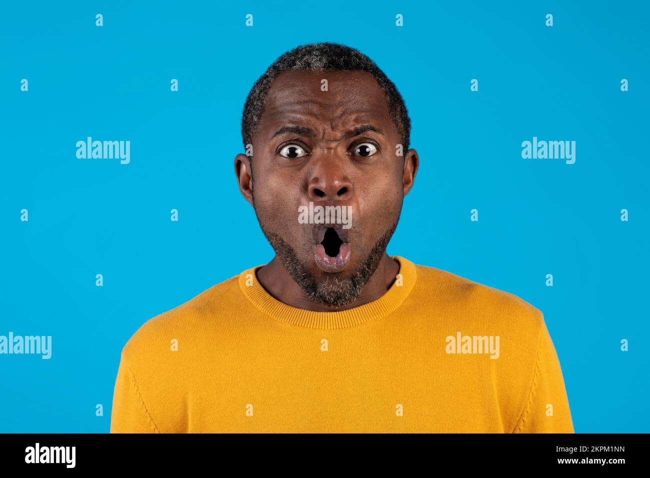 Shocked mature african american man looking at camera on blue Stock Photo