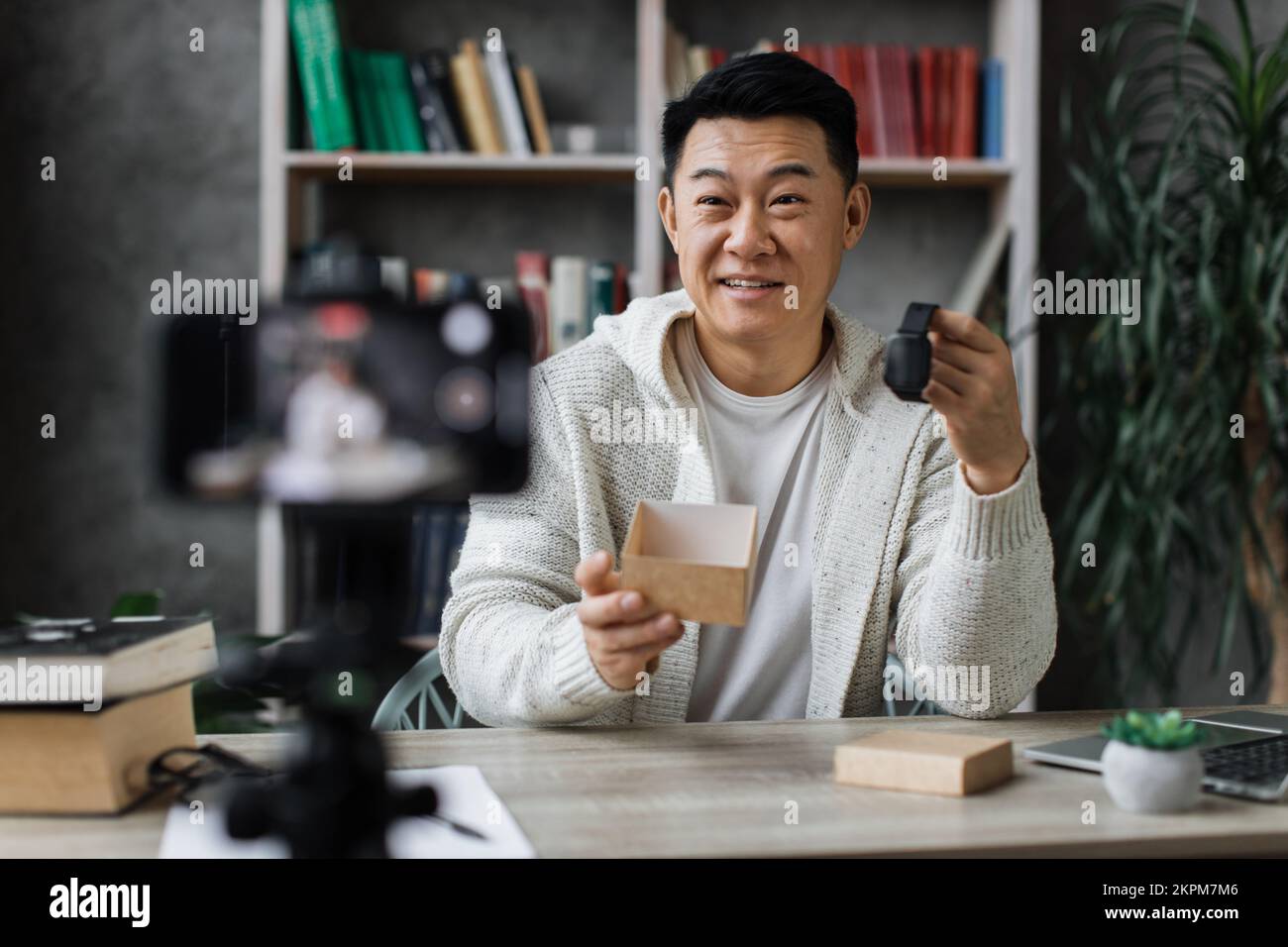 Asian man doing live stream while unpacking box with new smart watch