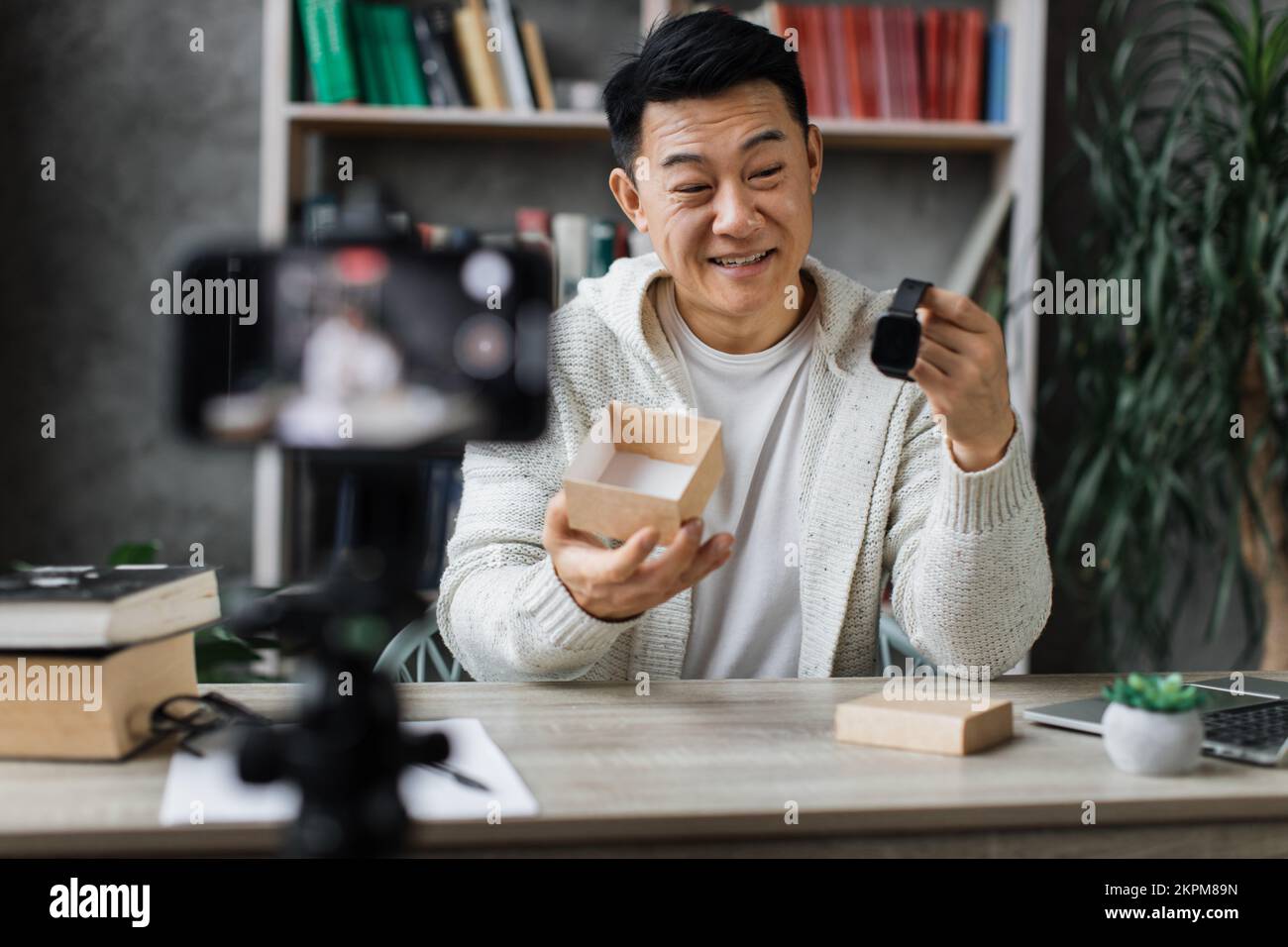 Asian man doing live stream while unpacking box with new smart watch