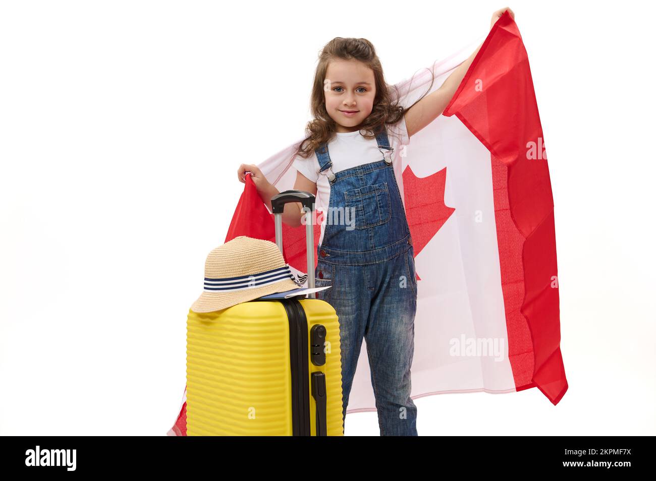 Little child girl carries Canadian flag and suitcase. Concept of study
