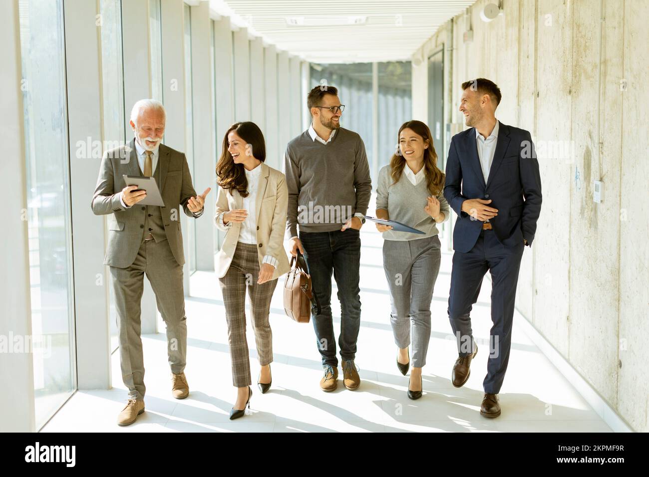 Group of corporate business professionals walking through office corridor on a sunny day Stock Photo