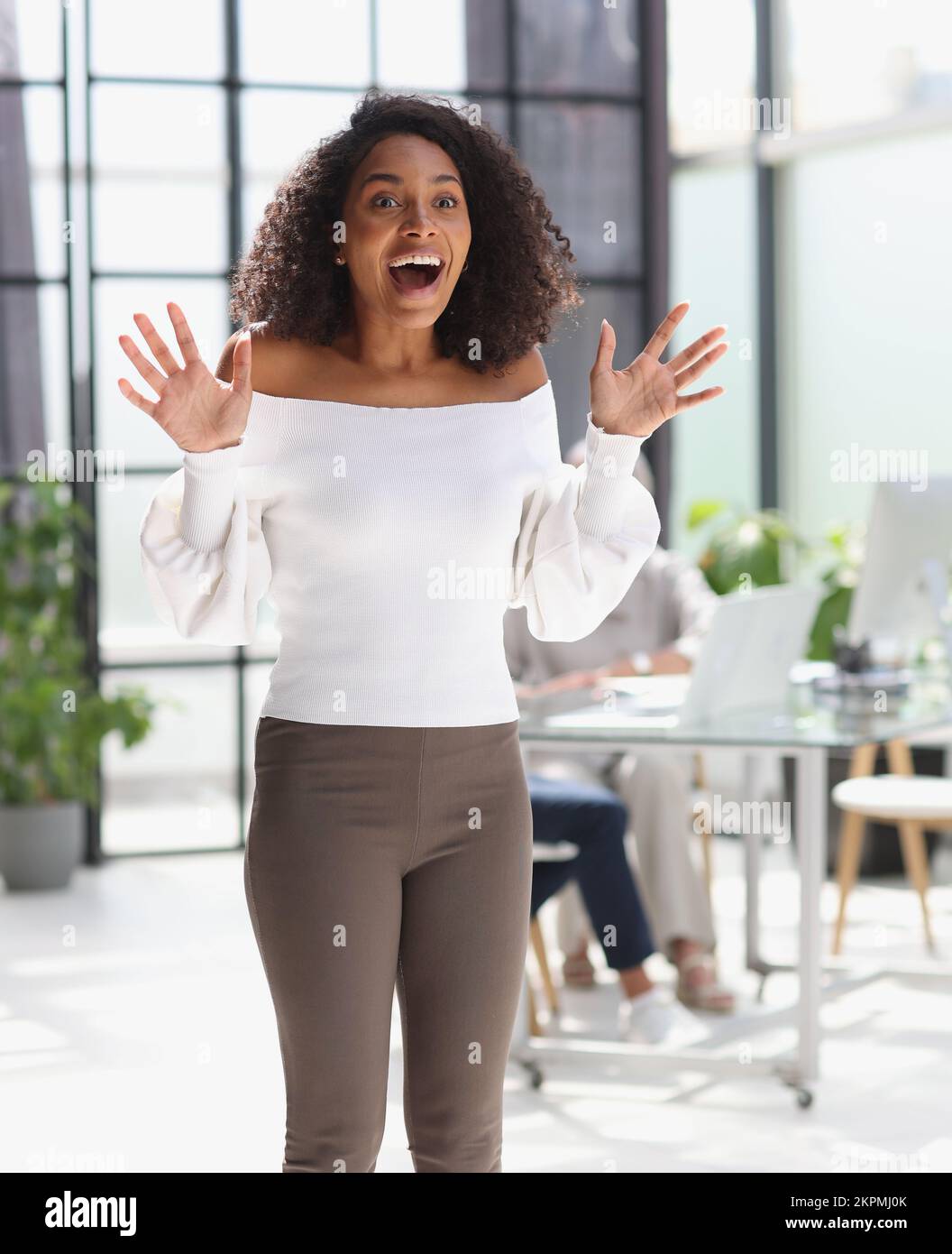 Portrait of a young attractive African American woman raised her hands ...