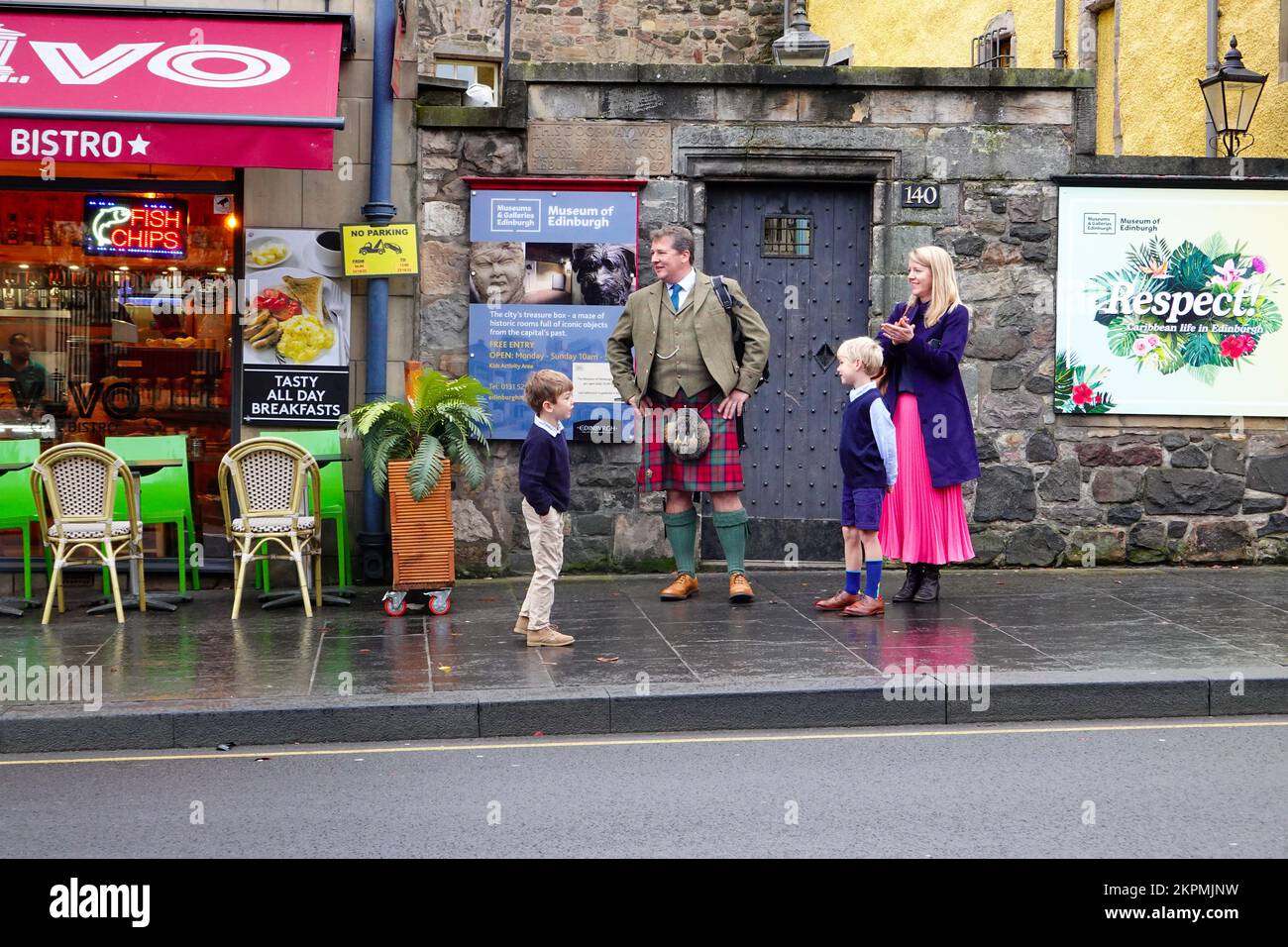 Young family, father wearing a kilt, watching an event at Canongate on the Royal Mile, just outside the Museum of Scotland. Stock Photo