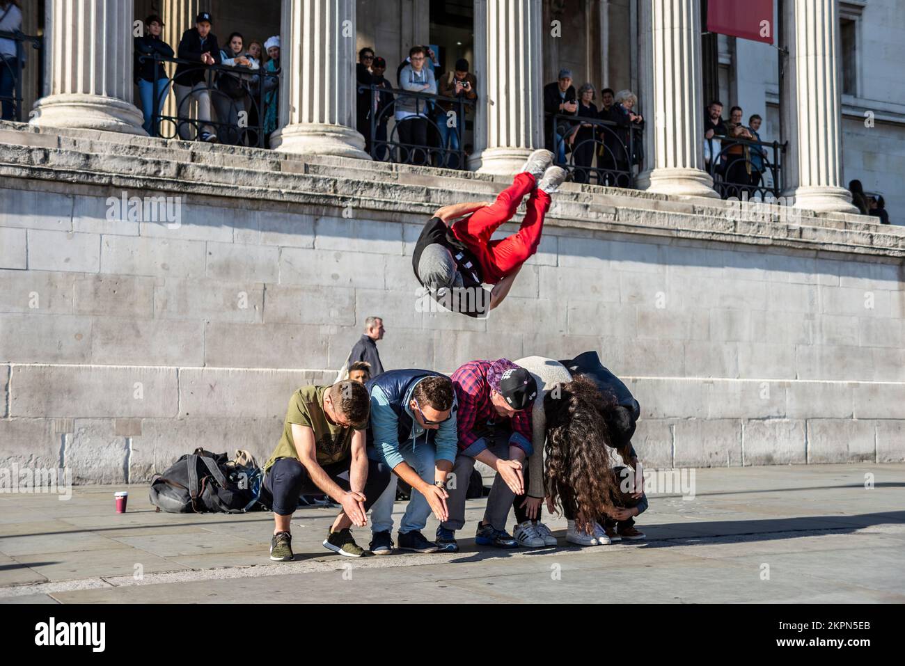 Gymnast. Street entertainer performing gymnastics outside The National Gallery using members of the public to jump over. Tourists involved. Acrobat Stock Photo