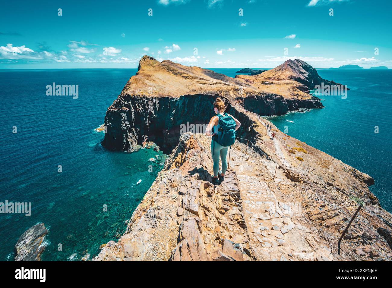 Description: Tourist enjoys the view of a strait from a steep cliff. São Lourenço, Madeira Island, Portugal, Europe. Stock Photo
