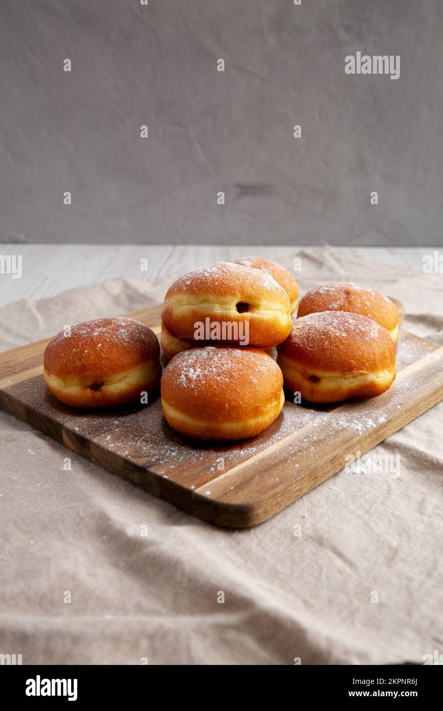 Homemade Apricot Polish Paczki Donut with Powdered Sugar on a Wooden Board, side view. Stock Photo