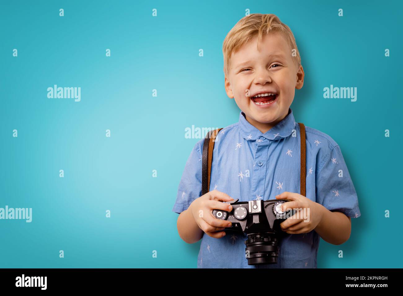 happy little boy with retro camera on blue background with copy space. photography courses Stock Photo