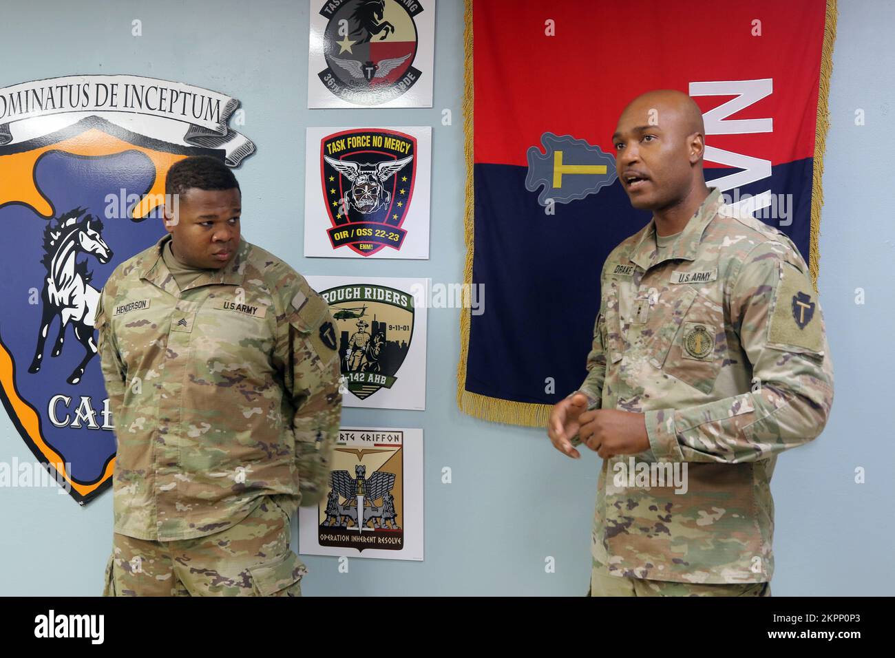 U.S. Army Chief Warrant Officer 2 Travarius M. Drake, force protection officer in-charge for 36th Combat Aviation Brigade, “Task Force Mustang,” 36th Infantry Division (right), introduces Sgt. Ishmel Henderson, airfield noncommissioned officer in-charge from Headquarters and Headquarters Company, 36th CAB, to the brigade command team during a command and staff meeting held at Task Force Mustang headquarters in Camp Buehring, Kuwait, Nov. 2, 2022. Henderson was recognized as Task Force Mustang's 'Hero of the Week' for his recent performance reviews and contributions to fellow Soldiers from acro Stock Photo