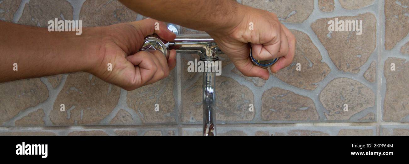 Image of a man's hands turning off the water tap. Saving and safeguarding the waste of water. Horizontal banner Stock Photo