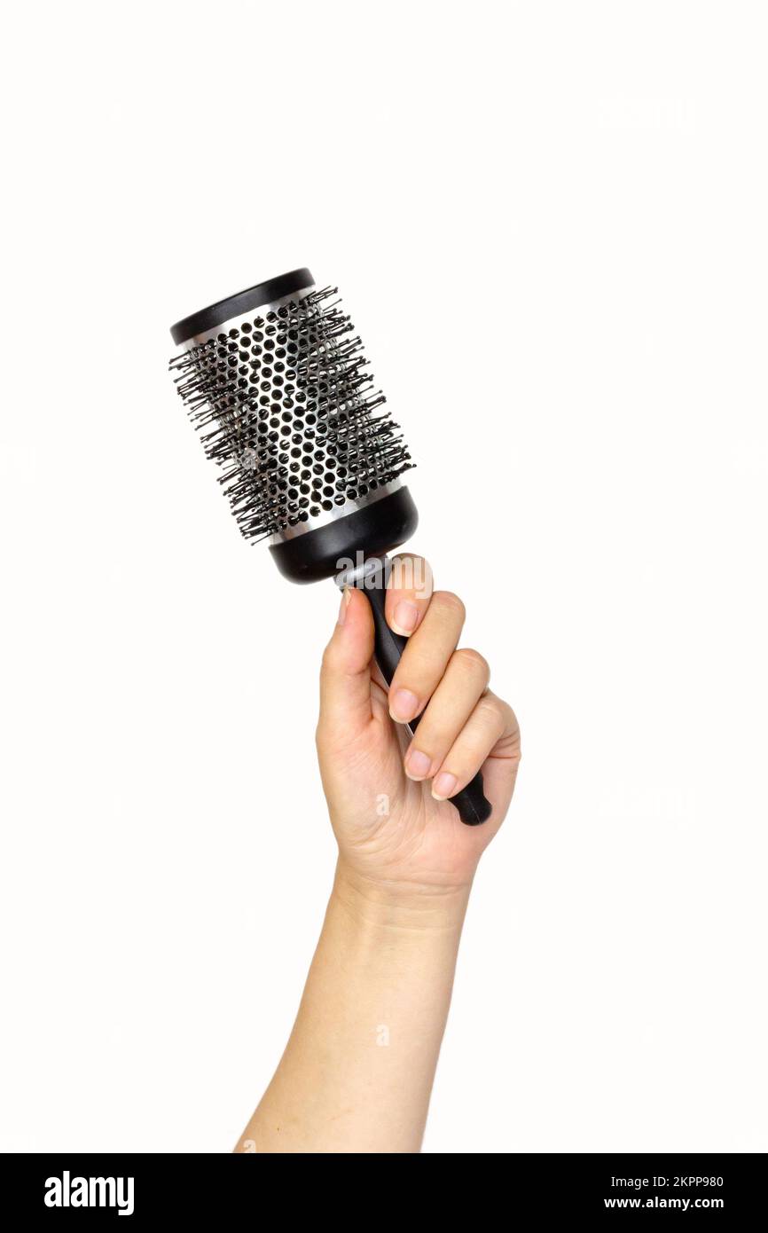 Female hand holding hair accessories black round comb over white background, copy space. Set of hairdresser's tools on white background Stock Photo