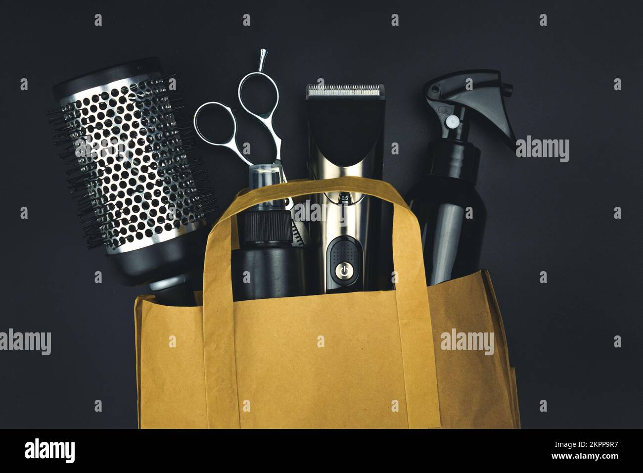 A set of hairdressing combs and scissors in black color in a craft package on black background Stock Photo