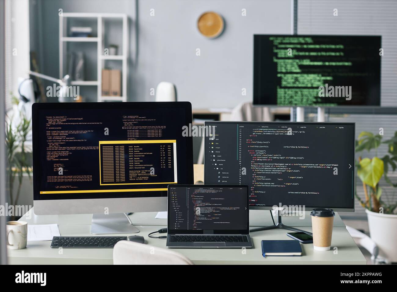 Computers and laptop with programming code in empty office of IT company Stock Photo