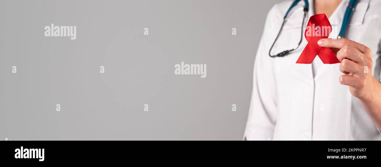 Red satin ribbon in doctors hand, symbol of HIV and AIDS awareness day ...