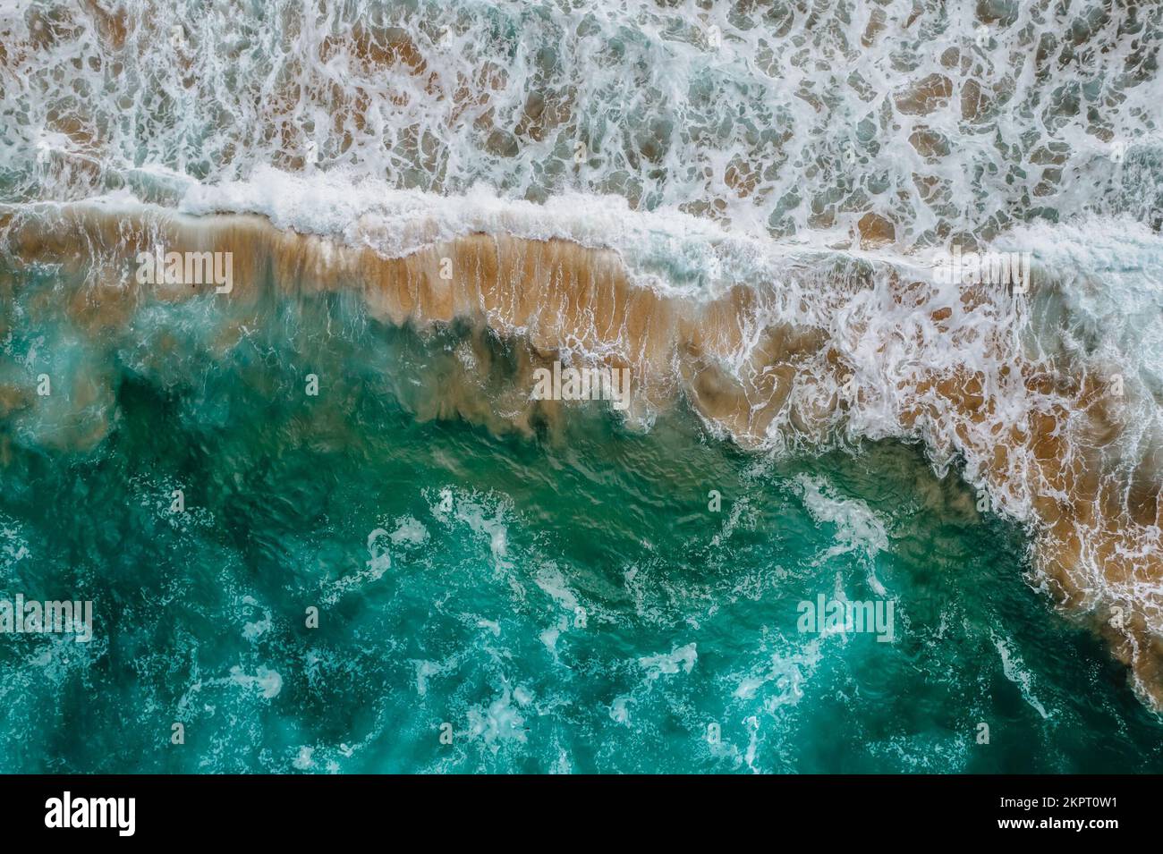 Wild high waves of Atlantic Ocean,turquise water,sandy beach in Portugal.Summer vacation travel concept.Top down view.Aerial view of wave breaking Stock Photo