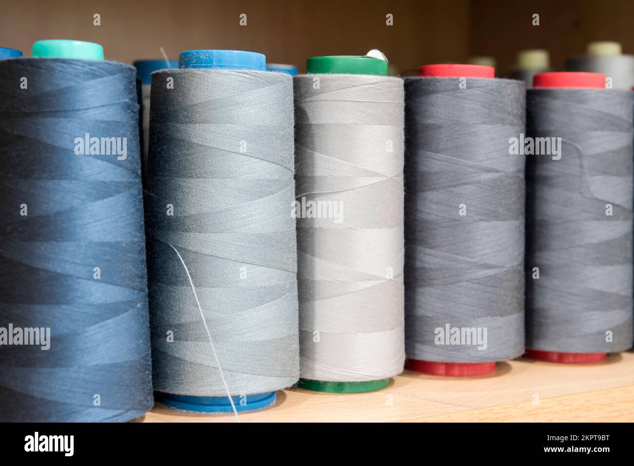 Sewing thread cones of different shade of colors on shelf in sewing ...