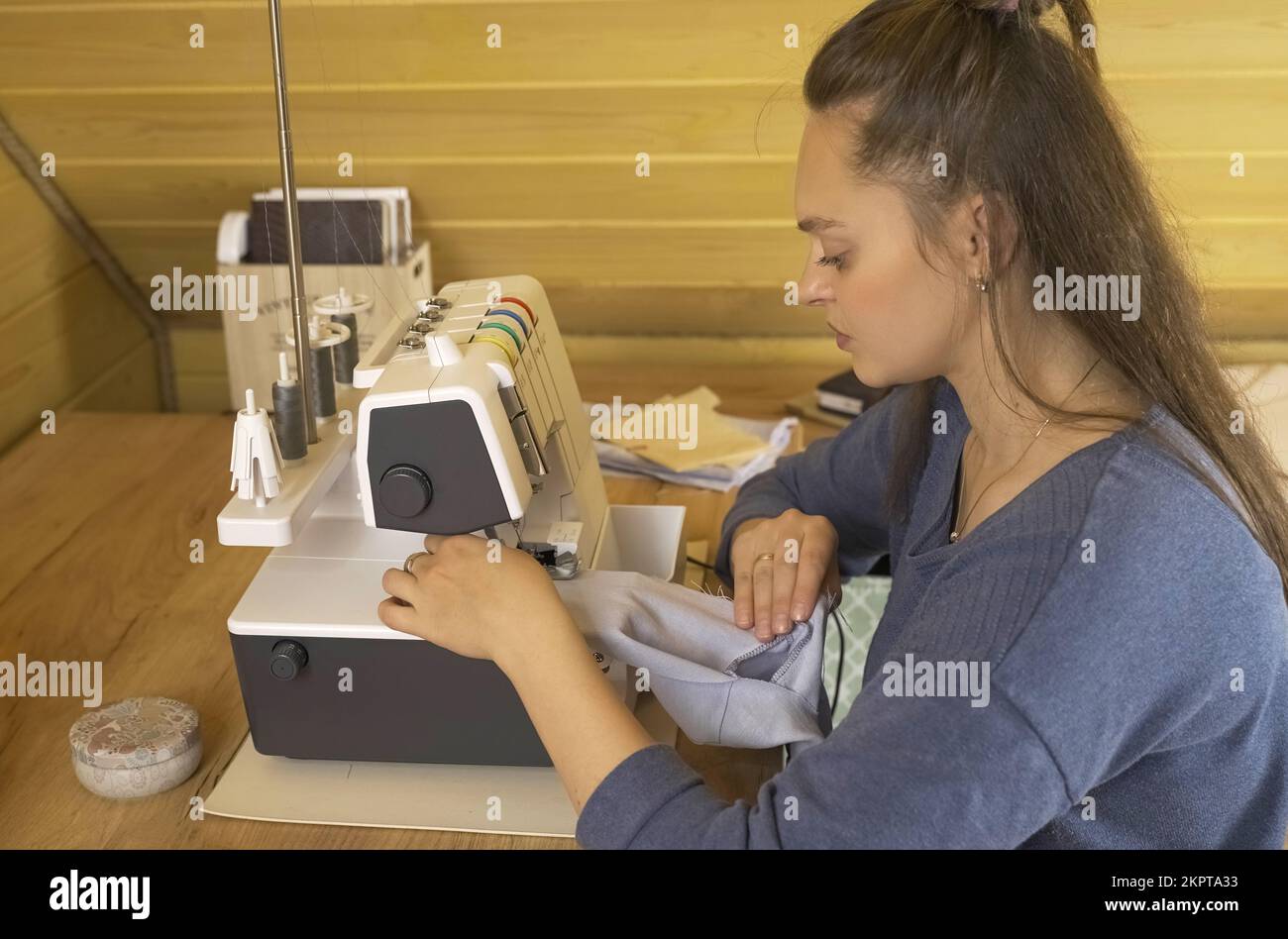 A woman designer works on an overlock sewing machine on tailoring. Small tailoring business