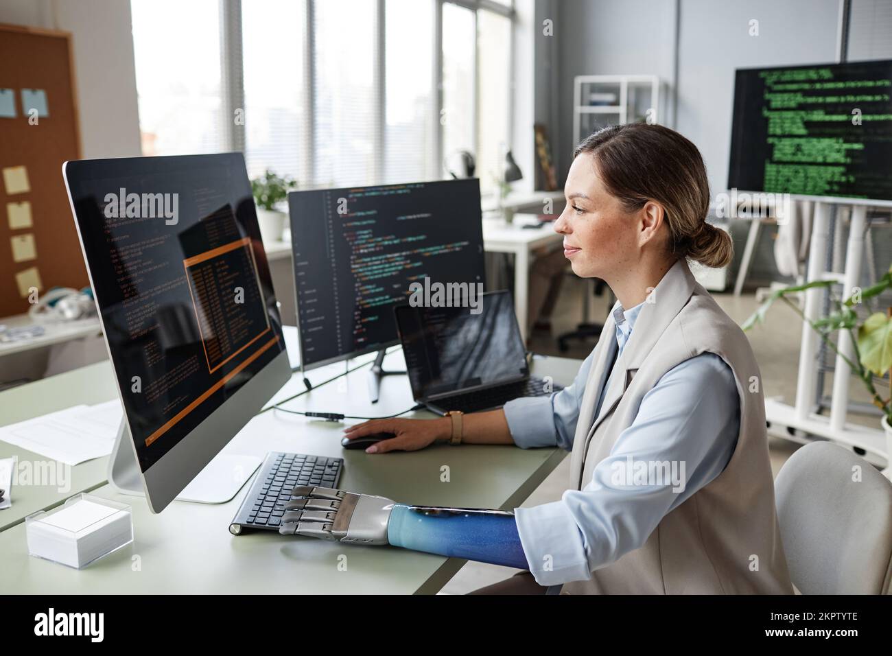 Positive software developer with bionic arm checking code on computer screen for bugs Stock Photo