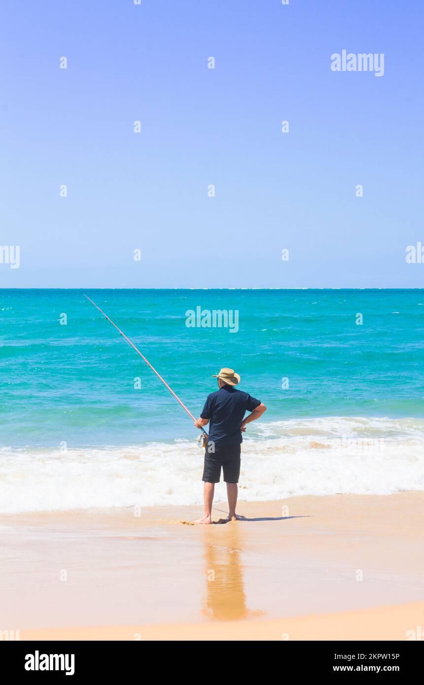 Vertical lifestyle photograph of a senior man fishing onshore in island paradise. Photographed: Amity Point, North Stradbroke Island, Queensland, Aust Stock Photo