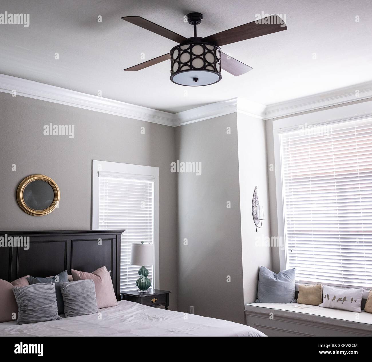 A light and bright gray master bedroom with a window seat, bed and a ...