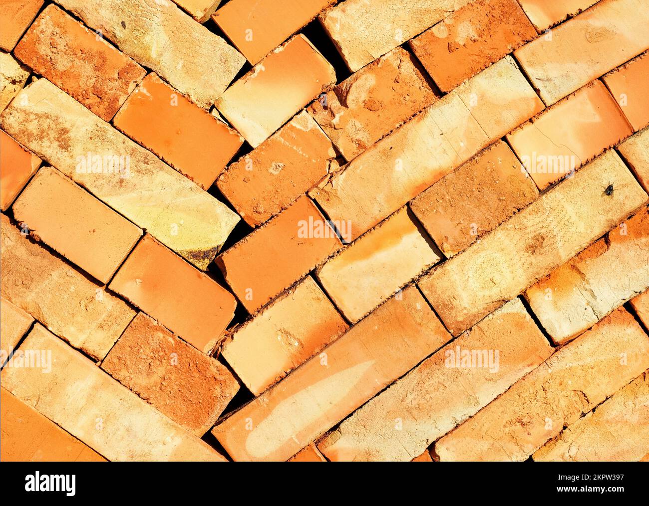 The orange brick is stacked in even oblique rows. Texture of a brick close-up in sunlight. Stock Photo