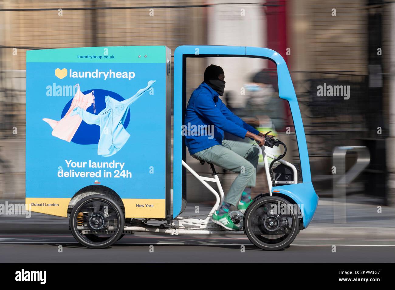A courier driving a laundryheap Electric Assisted Vehicles (EAV) which uses both pedal power and an electric motor. Laundryheap is a company which pro Stock Photo