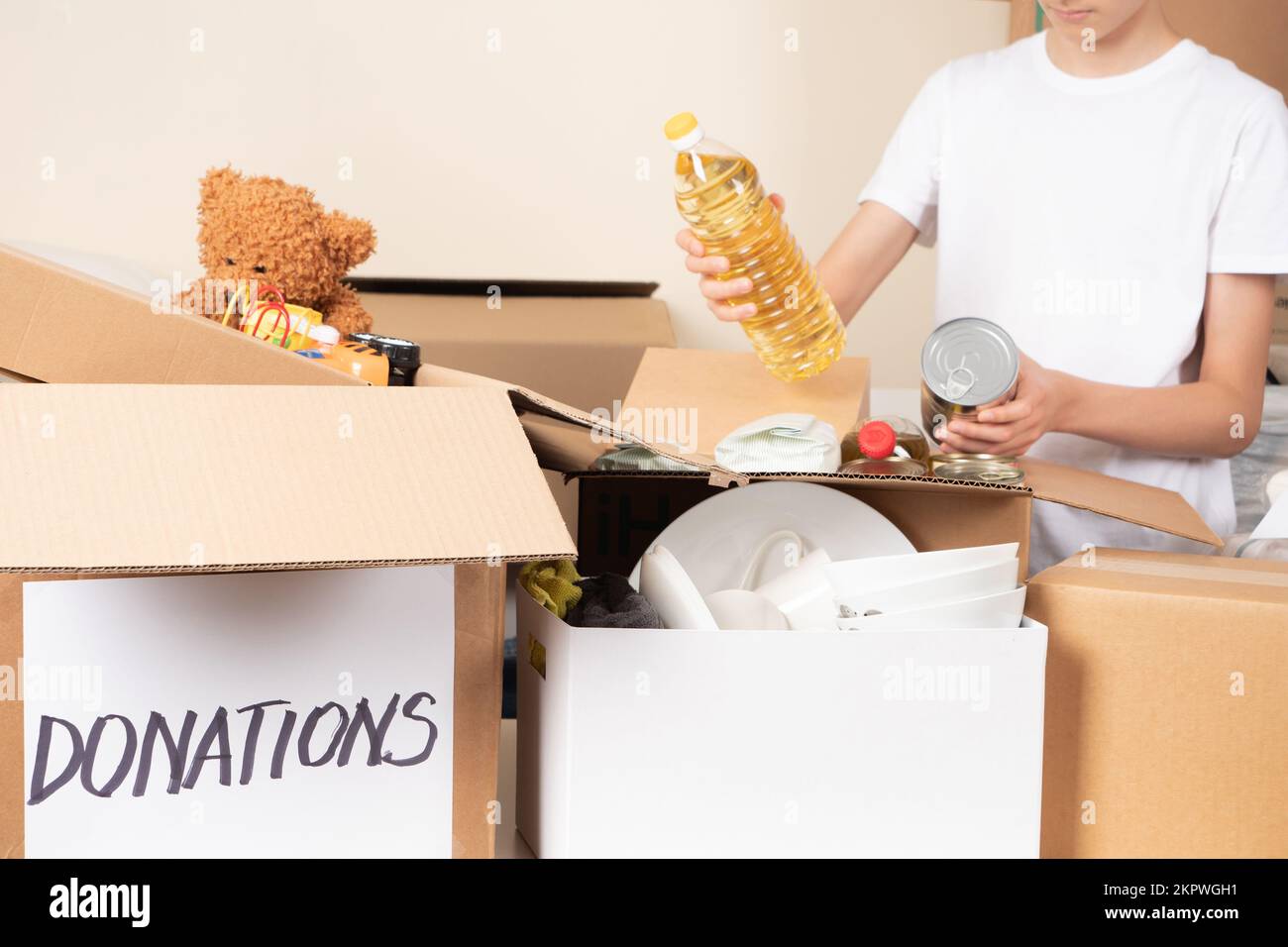 Teenage boy volunteer collecting food into donation box. Donation