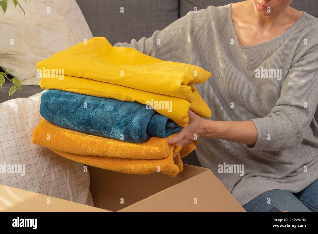 Female hands holding stack of bed linen. Woman preparing items and
