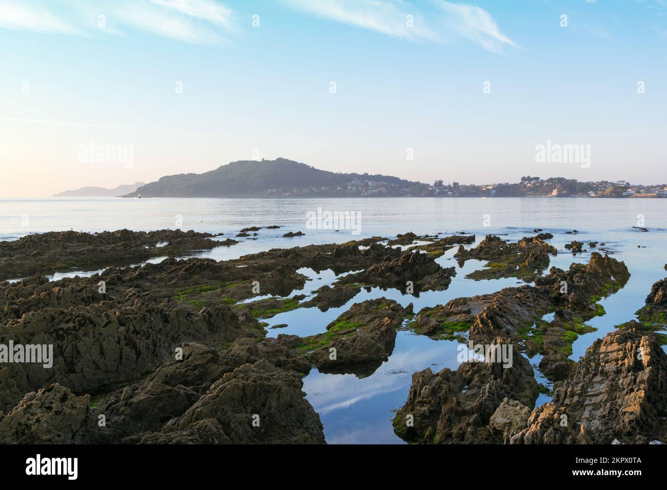 Coastal rock pools and distant view of town, Rias Baixas, Panxon, Nigran, Galicia, Spain Stock Photo