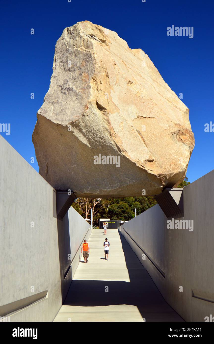 Two visitors set to walk under a suspended boulder at the Los Angeles County Museum of Art Stock Photo