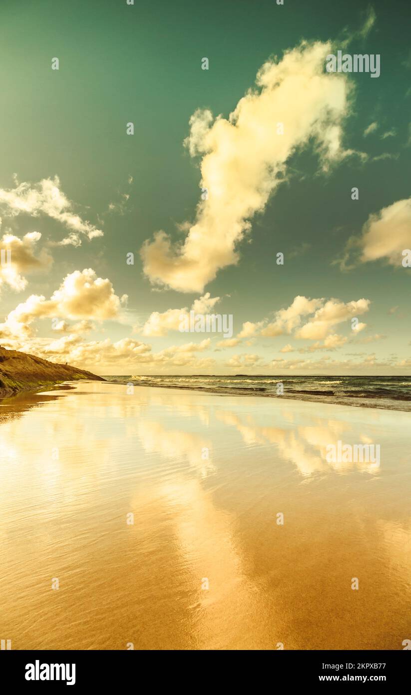 Placid landscape photo on smooth beach scene of low tides and clouded skies reflected. Deadman