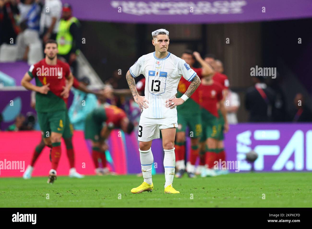 Lusail, Qatar. 28th Nov, 2022. Soccer, Qatar 2022 World Cup, Portugal - Uruguay, Preliminary Round, Group H, Matchday 2, Lusail Stadium, Uruguay's Guillermo Varela stands on the pitch as Portugal players (back) cheer. Credit: Tom Weller/dpa/Alamy Live News Stock Photo
