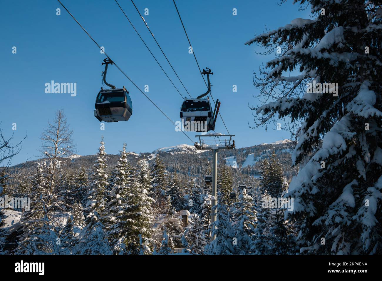 Ski resort - winter season - sky gondola, ski lift. Snowboarding, Sunny day, pure snow, forest pine trees, mountain peaks view. Winter olympic games. Stock Photo