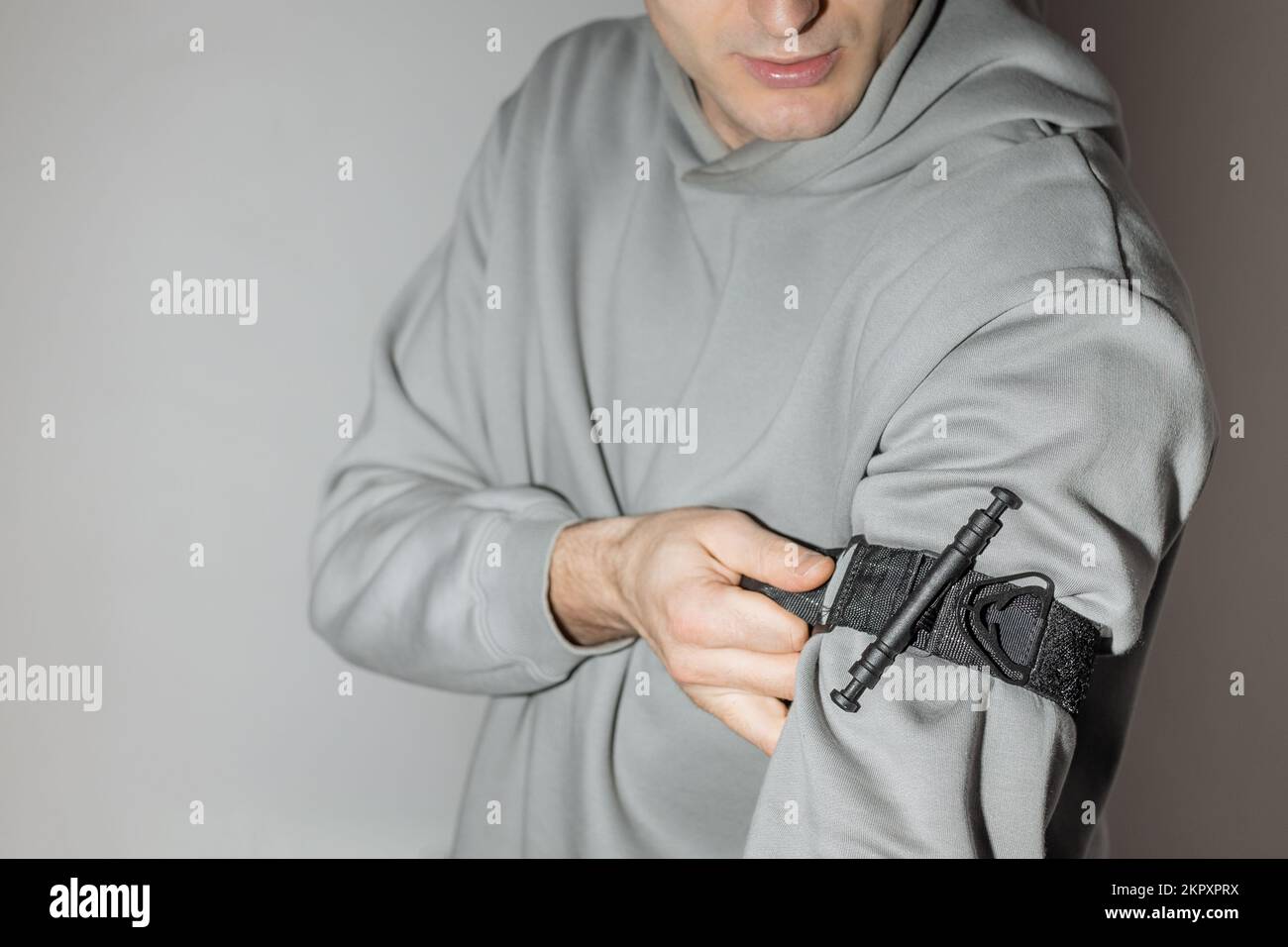 A person puts a tourniquet on his arm to prevent bleeding during first