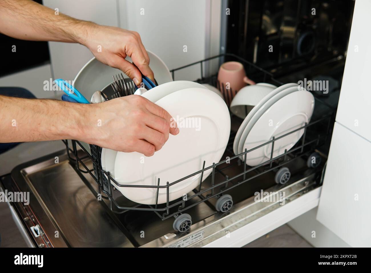 Washing dishes in the dishwasher. The man takes clean dishes from