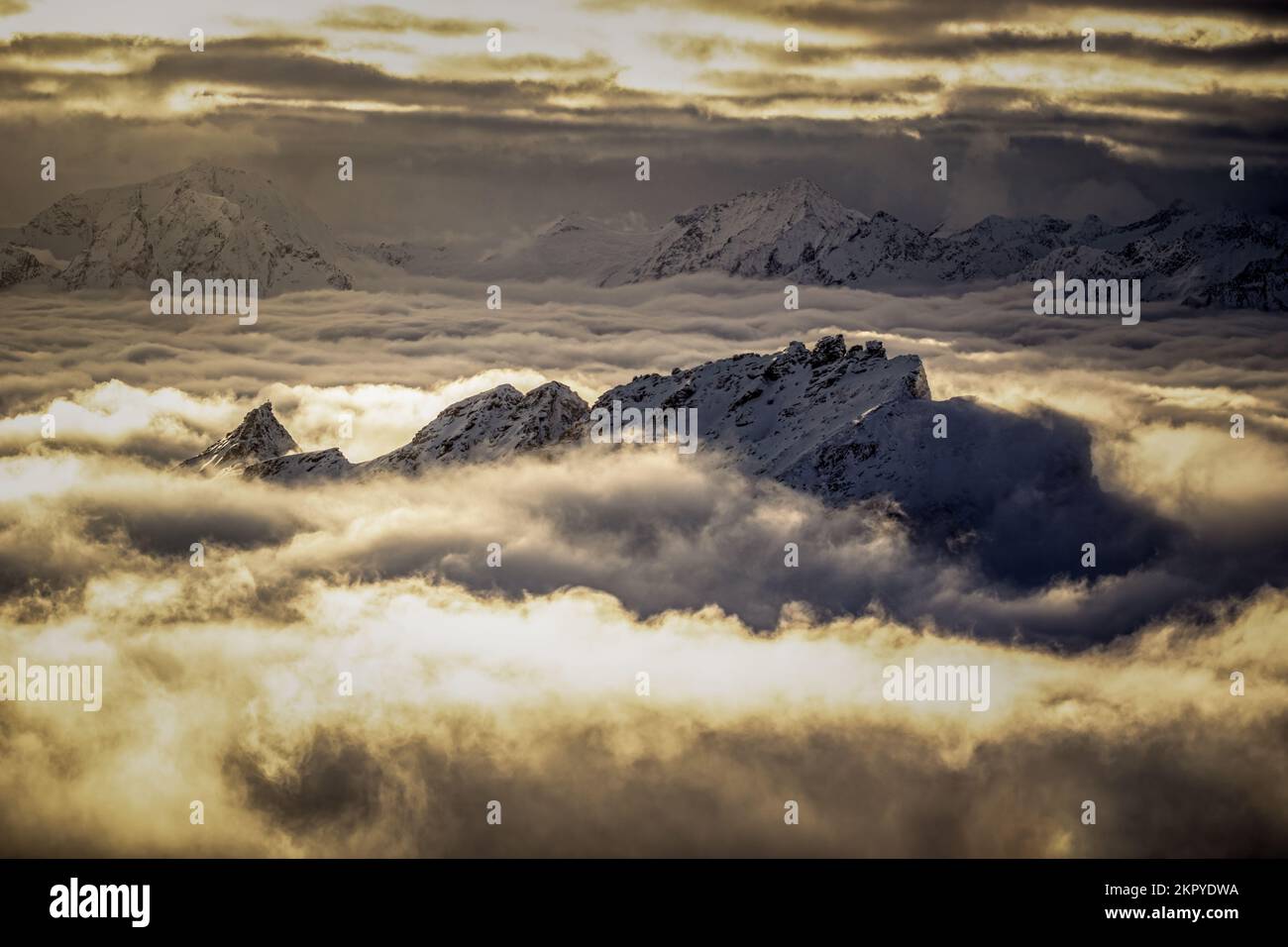 Snowcapped mountain peak through a cloud carpet at sunset, Salzburg, Austria Stock Photo