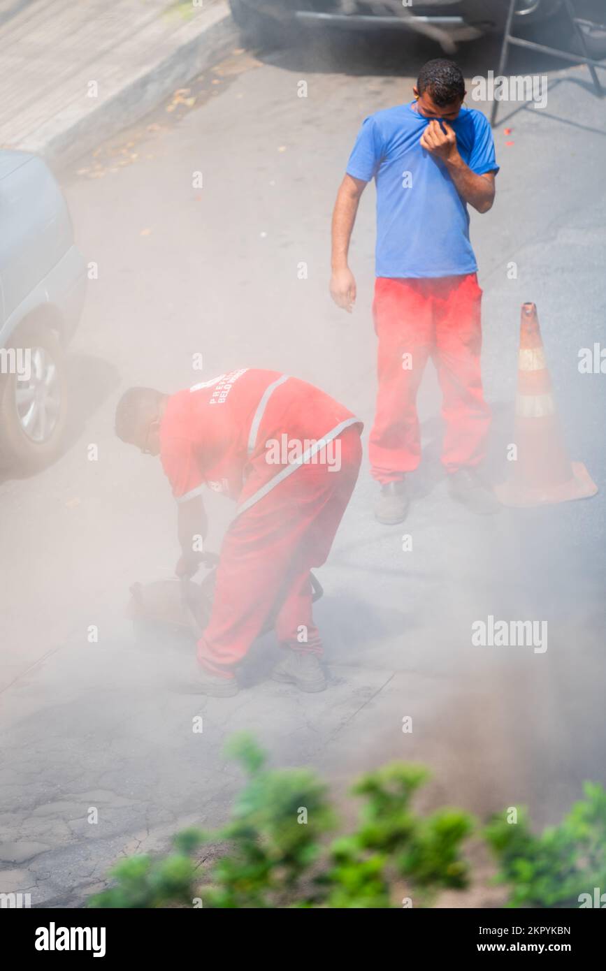 City of Belo Horizonte workers repairing a road with asphalt cutting machine causing a lot of dust at Gutierrez in Belo Horizonte, Brazil. Stock Photo