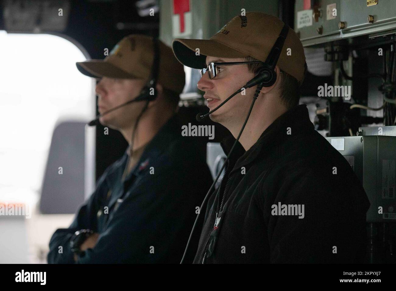 Master-at-Arms 1st Class Sean Hiller, left and Gunner’s Mate 3rd Class Thomas Bishop, right, stand watch in the pilothouse of the Arleigh Burke-class guided missile destroyer USS Thomas Hudner (DDG 116) as part of the Gerald R. Ford Carrier Strike Group, on Nov. 4, 2022. The first-in-class aircraft carrier USS Gerald R. Ford (CVN 78) is on its inaugural deployment conducting training and operations alongside NATO allies and partners to enhance integration the U.S. Navy’s commitment to a peaceful, stable and conflict-free Atlantic region. Stock Photo