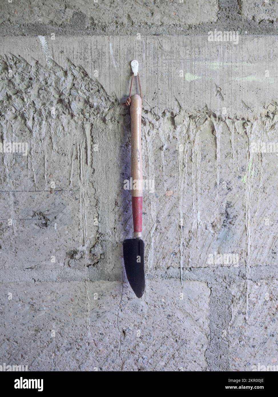Long handled forged trowel hanging on a masonry wall in Jinotega, Nicaragua.  It was imported by a US citizen retiring to Nicaragua. Stock Photo