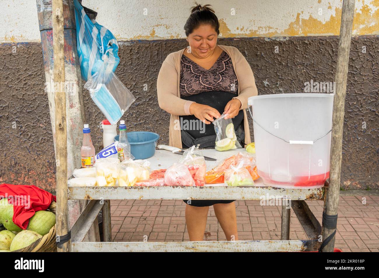 Street vendor put food in plastic bag to sell to passersby in Jinotega, Nicaragua.  This is common all  over Latin America. Stock Photo