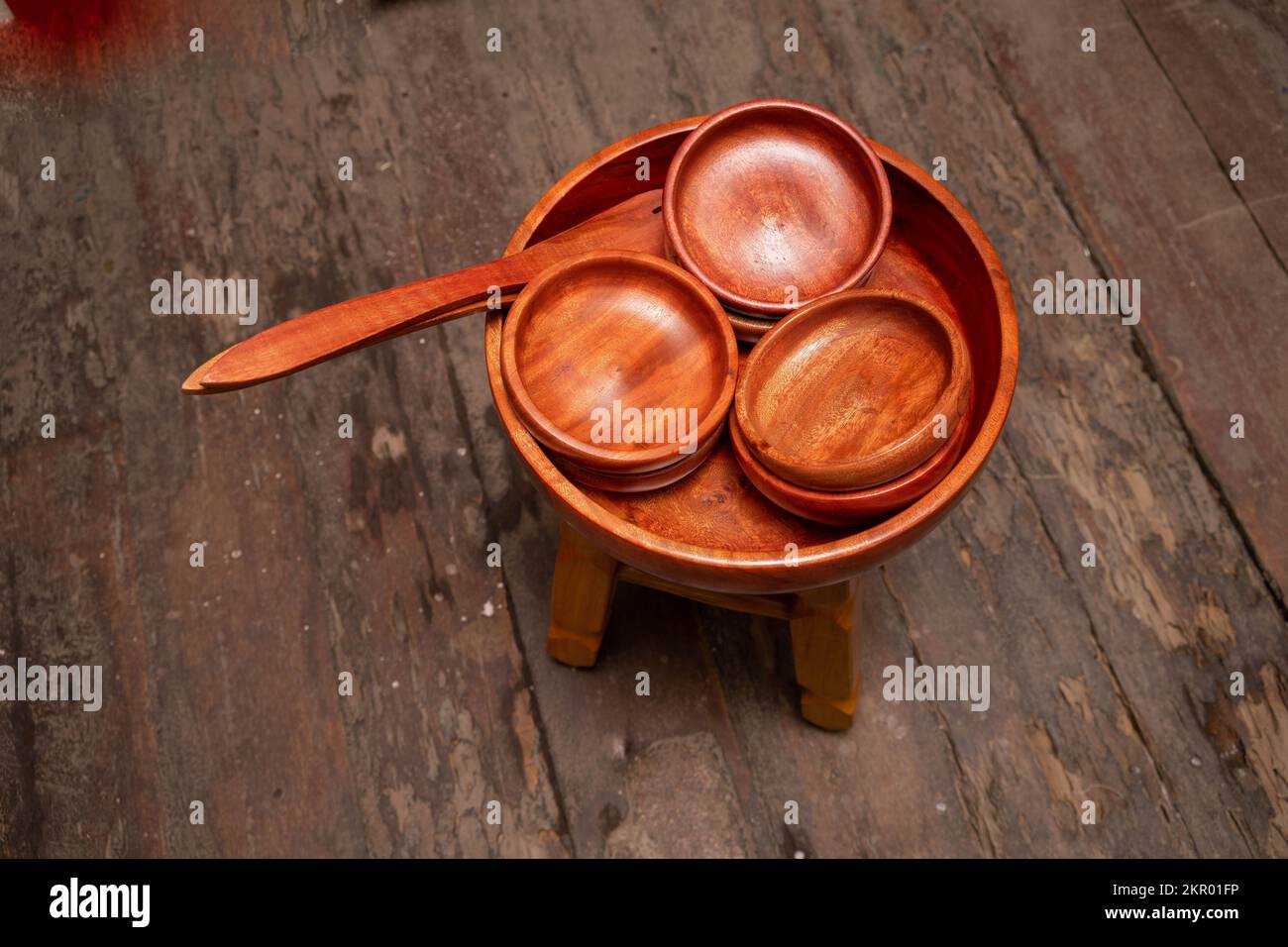 Wooden salad serving bowl and individual smaller bowls with a serving spoon sitting on a stool in a craft shop in Nicaragua. Stock Photo