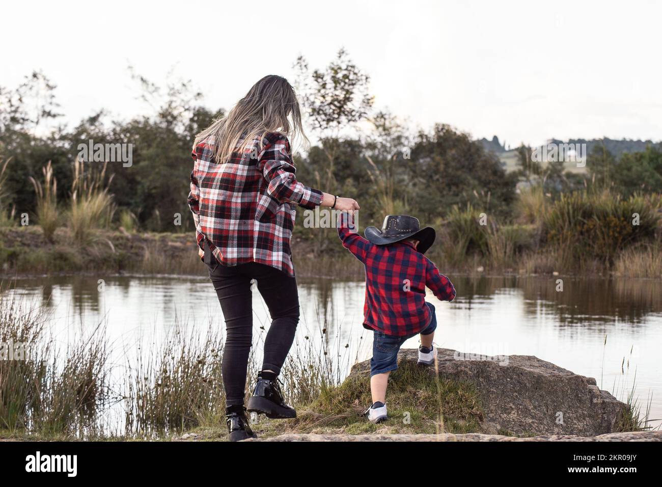 mother helping her son to climb a stone Stock Photo