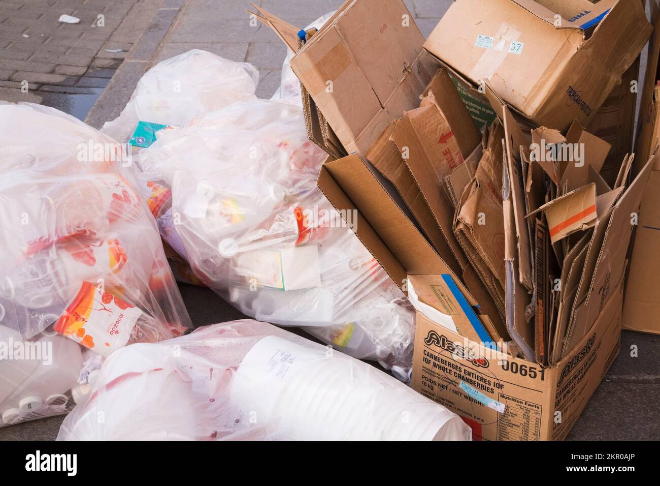 Cardboard boxes and plastic bags on city sidewalk ready to be picked up