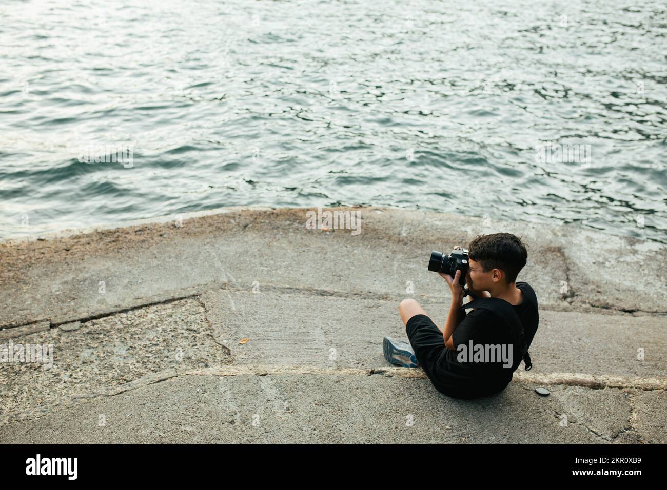 Boy Sits By Lake Como And Photographs The Scene Stock Photo