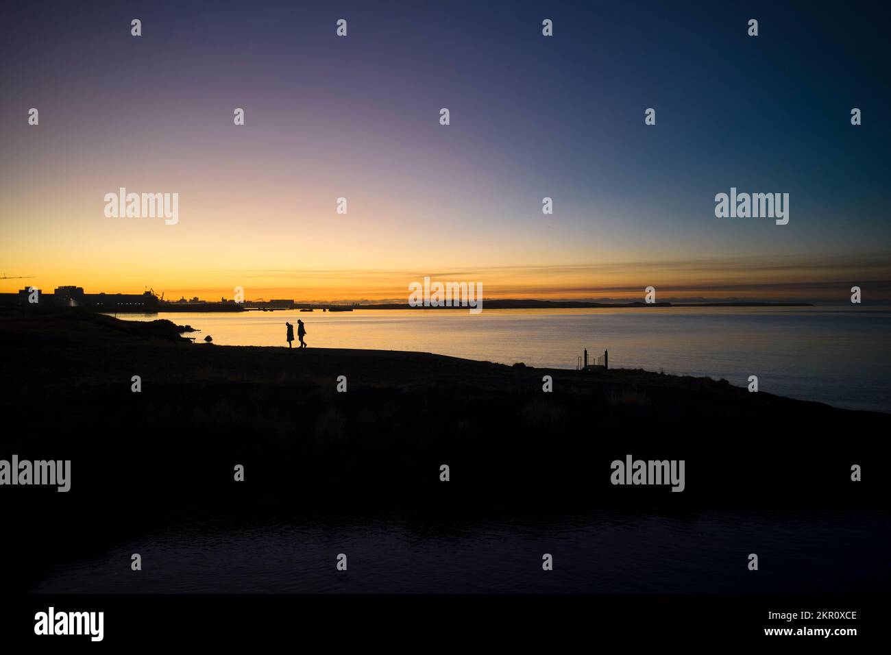 People walking on beach at sunset Stock Photo